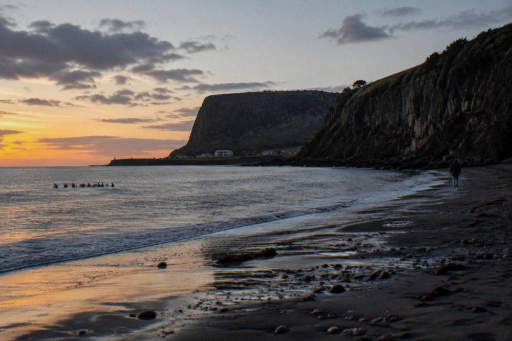 A dark beach at dusk with the last light fading over the water