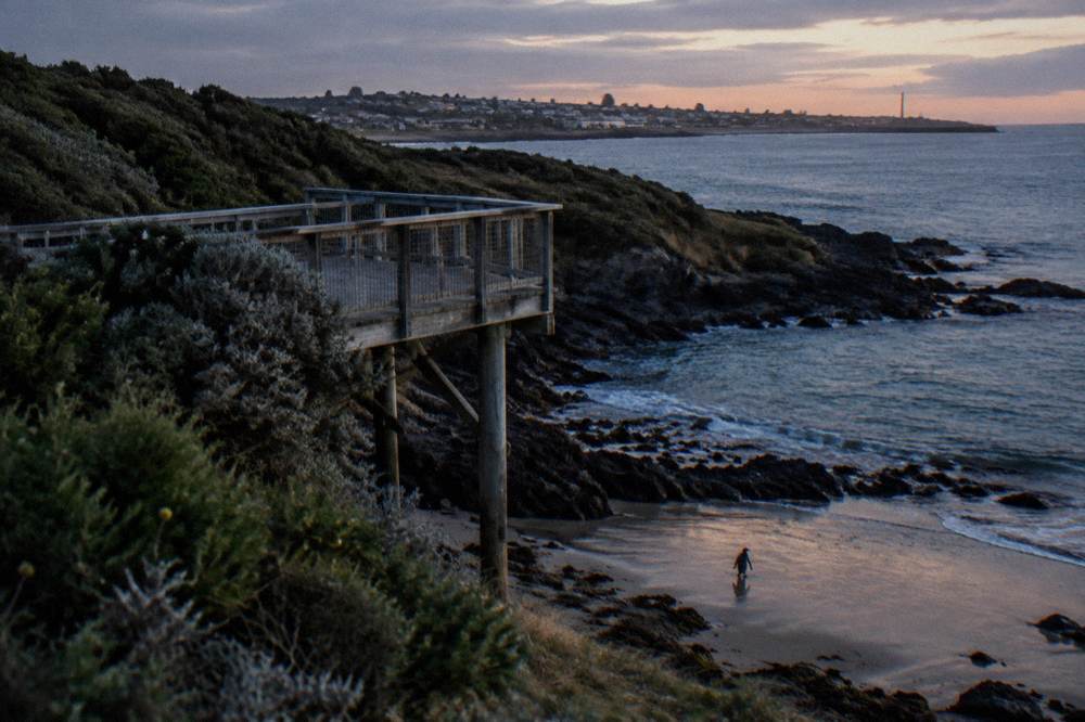 A wooden viewing platform beside a dark beach on the north west coast of Tasmania